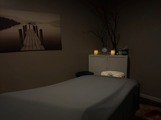 Peaceful dimly lit private spa room with prepared treatment bed